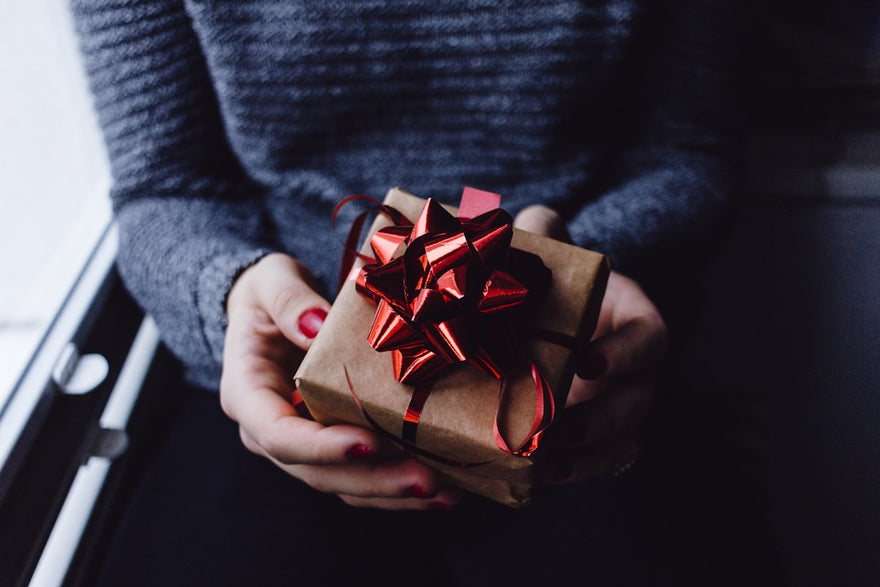 Persona sosteniendo una caja de regalo envuelta para celebrar Amor y Amistad