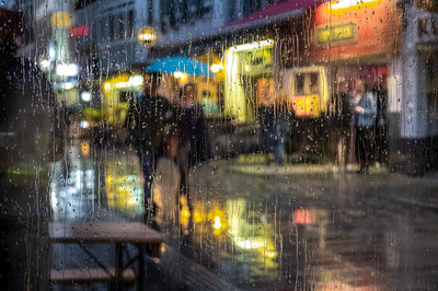 Personas caminando por una calle en un día de lluvia con paraguas