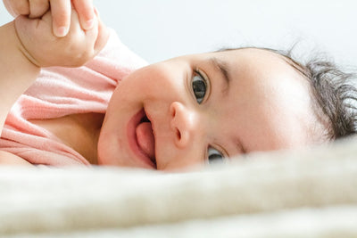 Bebé sonriente sobre una manta suave — cuidado de la piel del bebé