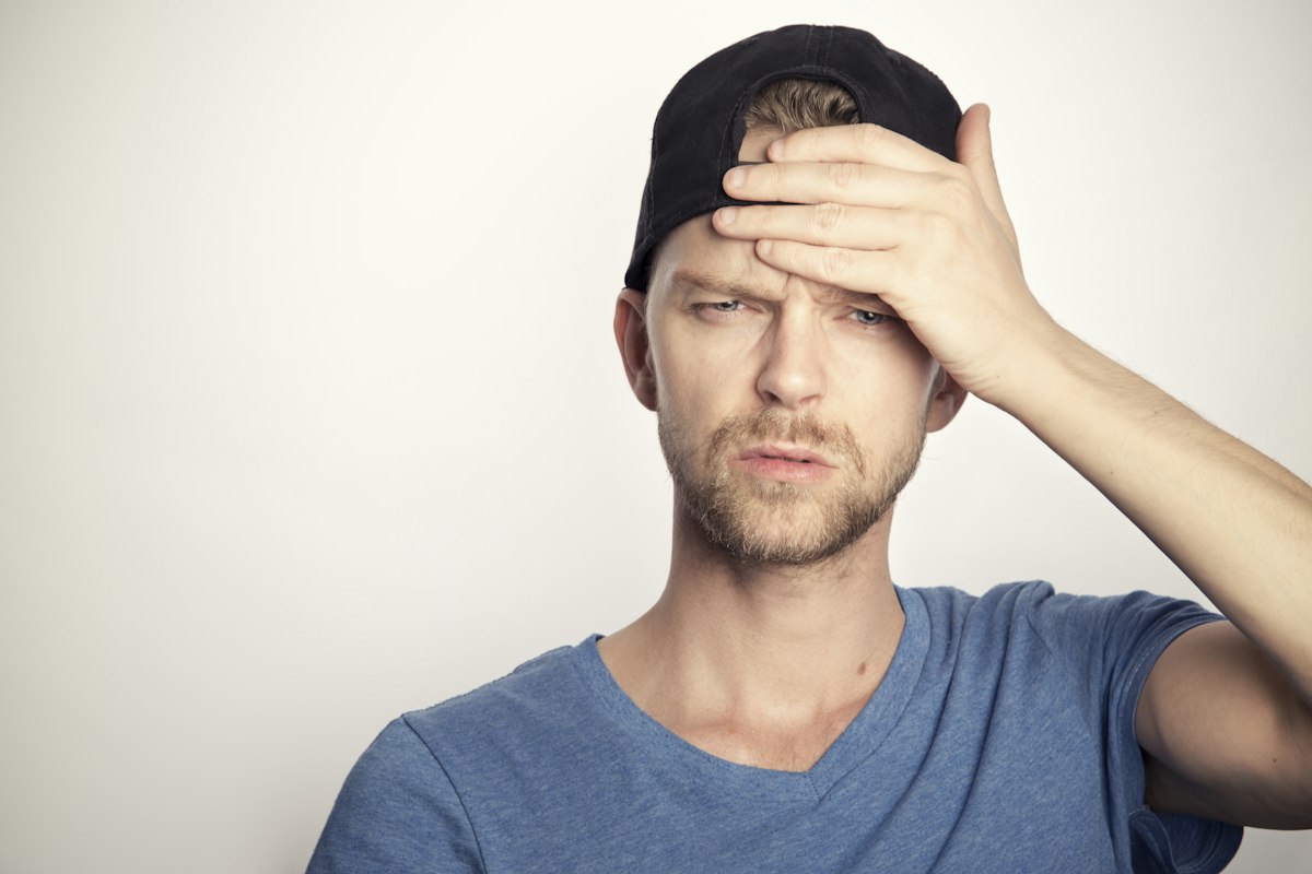 Hombre con dolor de cabeza llevándose la mano a la frente