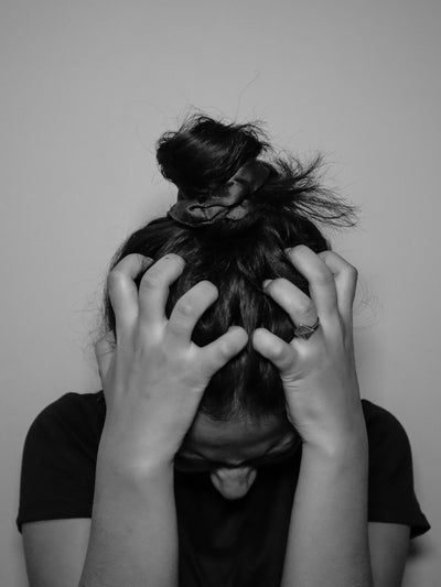 Mujer con dolor de cabeza cubriéndose el rostro con las manos, síntoma típico de migraña