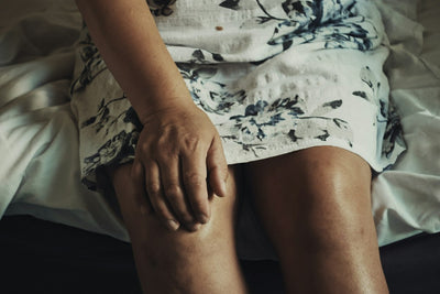 Persona sentada tocándose la rodilla por molestia articular