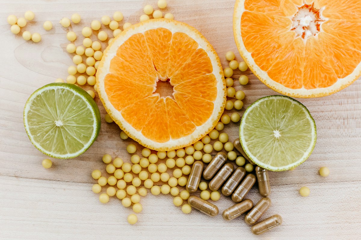 Frutas cítricas junto a cápsulas de suplementos vitamínicos